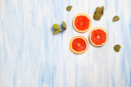 A top view of fresh grapefruit slices and dry leaves isolated on the white-blue backgroundの写真素材