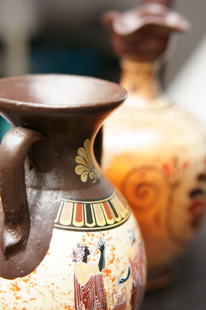 A vertical shot of Greek vintage ceramic vases on the table with a blurry backgroundの写真素材