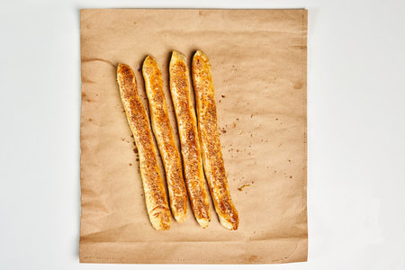 A top view of homemade breadsticks with seasonings on a white surface