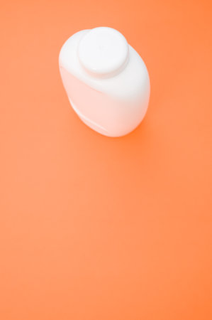 A vertical shot of a white blank plastic bottle on an orange surfaceの写真素材