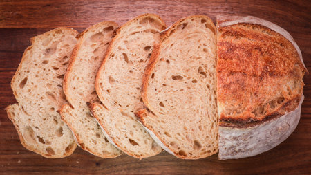 An overhead shot of a freshly baked, sliced sourdough bread on a wooden boardの写真素材