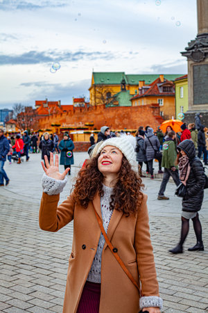 A smiling Caucasian female with red lipstick trying to catch bubbles in Warsawの写真素材