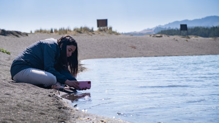young woman taking photo with cell phone at a lagoonの写真素材