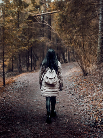 A vertical shot of a female backpacker walking on a path through the forestの写真素材