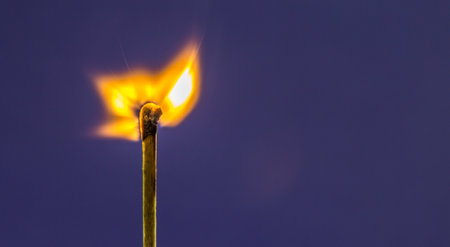 A closeup shot of a burning match on a purple backgroundの写真素材