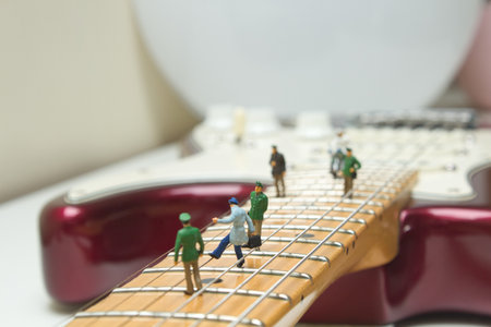 A closeup shot of small figures of people on an electric guitarの写真素材
