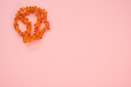 A closeup shot of an amber beads necklace on a pink surfaceの写真素材