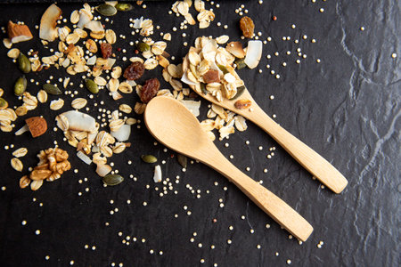 A top view of healthy and delicious muesli with wooden spoons on a black backgroundの写真素材