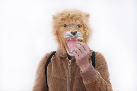 A man with a roaring lion full mask holding a daisy posing for camera isolated on white background
