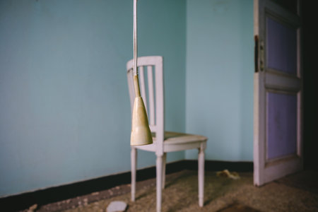 A selective focus shot of a hanging lamp in a room next to a chairの写真素材