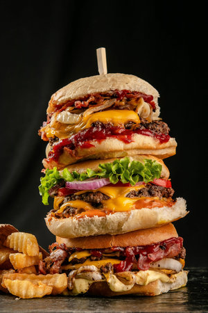A vertical shot of a multi-layer hamburger on an isolated black backgroundの写真素材