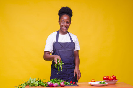A horizontal shot of a young attractive African cook holding greens/ orange backgroundの写真素材