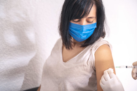 A closeup of a hand injecting a vaccine into a female-concept COVID19 vaccineの写真素材