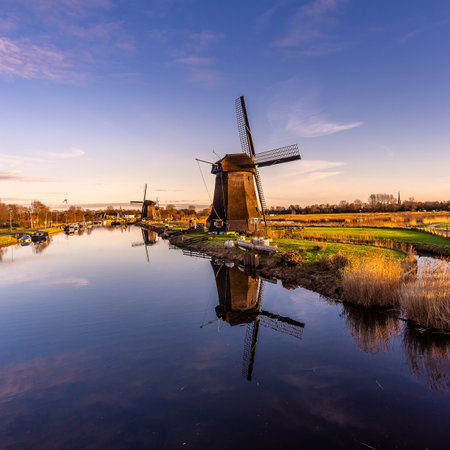 An eerie scenery of old windmills at Kinderdijk by the lake in the starry night in Alkmaar city, Netherlandsのeditorial素材