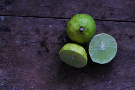 A top view shot of a dark wooden surface with sliced and whole lemons