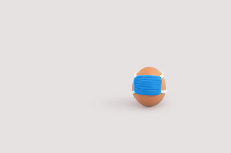 A chicken egg with a sanitary mask isolated on a gray background