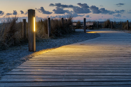 A wonderful sunrise over a wooden path with lanterns alongside, North Sea coast, Netherlands