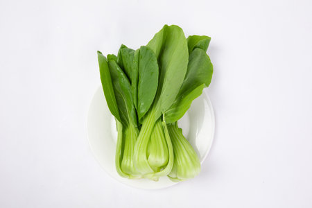The bok choy cabbage with water drops on the plate isolated on white backgroundの写真素材