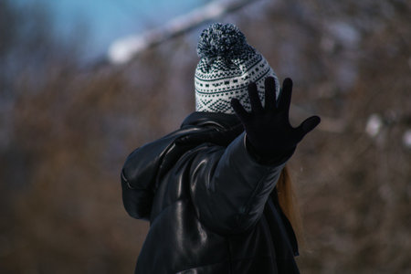A shallow focus shot of a young female in a knitted hat posing at cameraの写真素材