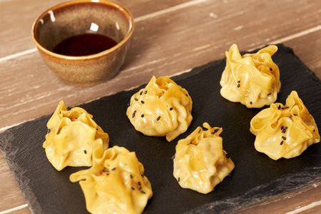 A view at prawn shumai traditional Chinese dumplings on a black rustic board on a wooden tableの写真素材
