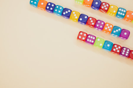 Colorful dice in a row isolated on a beige backgroundの写真素材