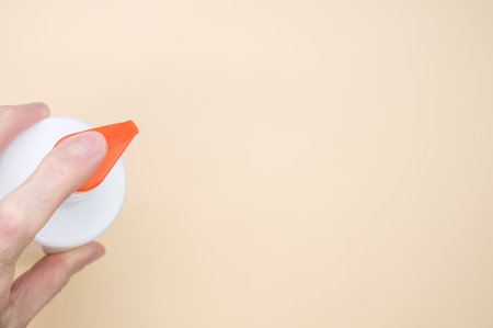 A top view of a person using a plastic pump dispenser bottle on a beige surfaceの写真素材