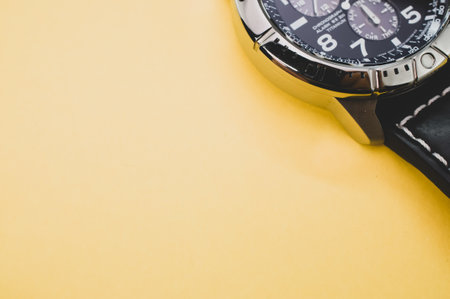 A closeup shot of a black classic wrist watch isolated on a yellow backgroundの写真素材
