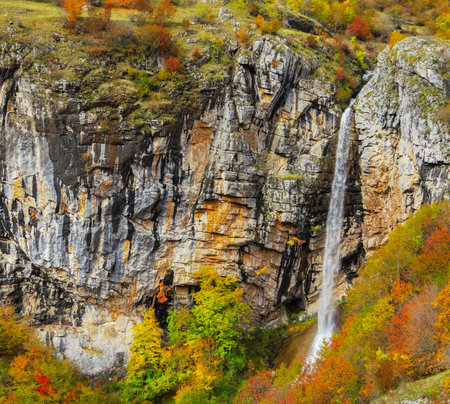 A nice shot of a waterfall in colorful autumn dayの写真素材