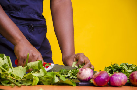 A closeup shot of an African cutting vegetables/orange backgroundの写真素材