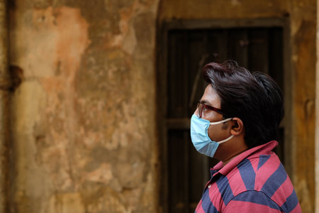 A closeup shot of an Indian man with a mask on the wall background