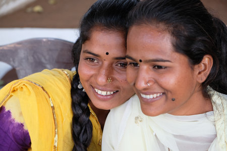 A portrait of two happy smiling Indian female friends enjoying their time in a cafe looking at somethingの写真素材