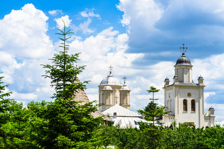 an orthodox church monastery near Bucharest, Romania surrounded by green trees under a cloudy sky