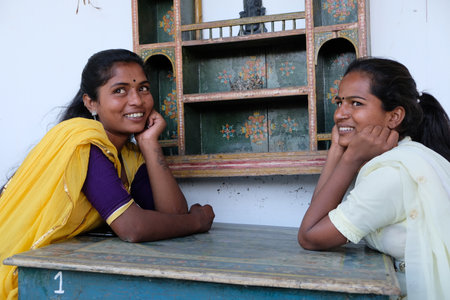 A smiling two Indian woman looking at something with hands in their chin
