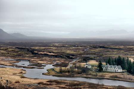 A landscape of the Thingvellir National Park surrounded by hills under a cloudy sky in Icelaの写真素材