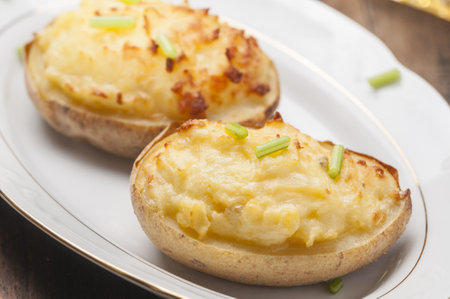 A closeup shot of stuffed baked potatoes with cheese and egg on a white plateの写真素材