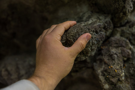 A female hand touching a rock on the wall; connection to natureの写真素材