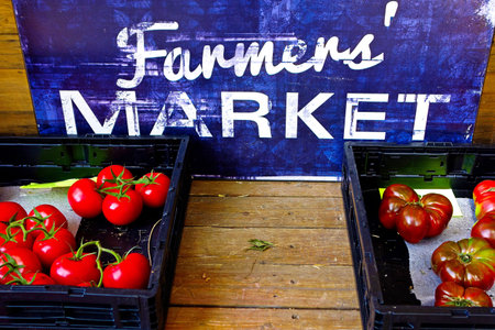 A closeup of two baskets filled with fresh tomatoes on a wooden table in the farmer's marketの写真素材