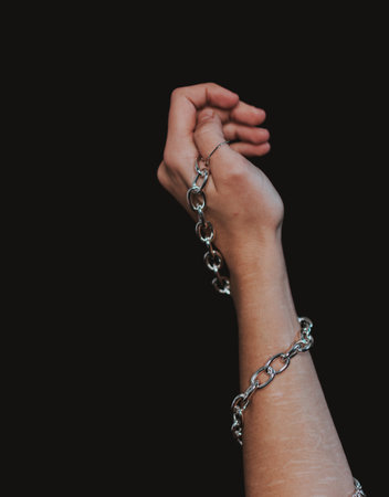 A vertical shot of male hand stretched upwards with a thick silver chainの写真素材