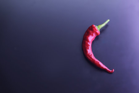 A top view of a red hot chilli pepper isolated on the dark background with a copy spaceの写真素材