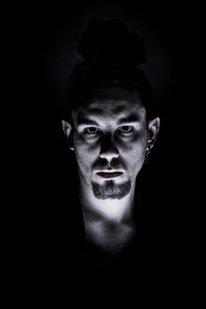 A vertical dark dramatic shot of a male with a serious expressionの写真素材