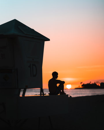 A silhouette of a boy sitting near the cabin on the sunset backgroundの写真素材