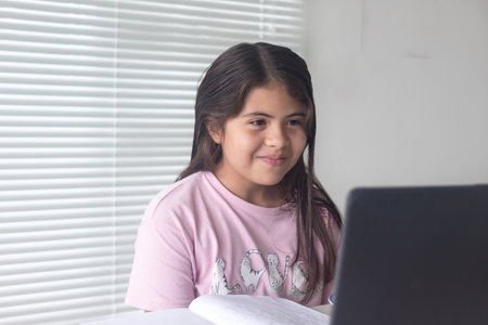 A Colombian Hispanic girl studying through a video call on a laptop at home,New normalの写真素材