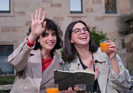 A view of two women having breakfast and saying hello to their friend on the street