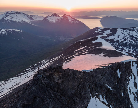 A beautiful landscape of high snowy rocks against sunset sky background in Norway