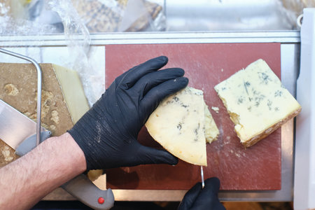 A male staff slicing a block of cheese in a local supermarketの写真素材