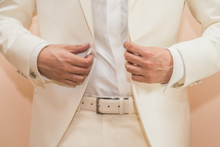 A closeup shot of a man buttoning his white suitの写真素材