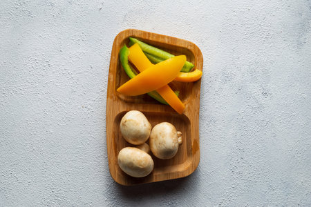 A top view of fresh mushrooms and chopped peppers on a wooden plateの写真素材