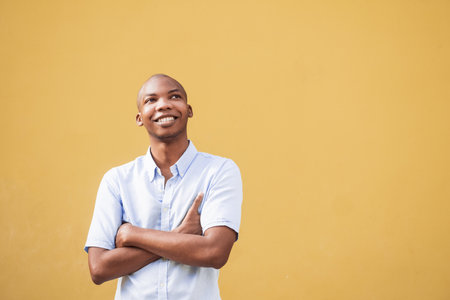 A happy Afro American in a white shirt posing at camera on a yellow backgroundの写真素材