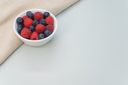 A closeup shot of fresh blueberry and raspberry on a white bowlの写真素材