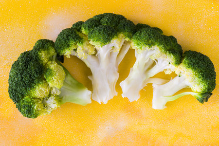 A closeup shot of blanched broccoli isolated on a yellow backgroundの写真素材